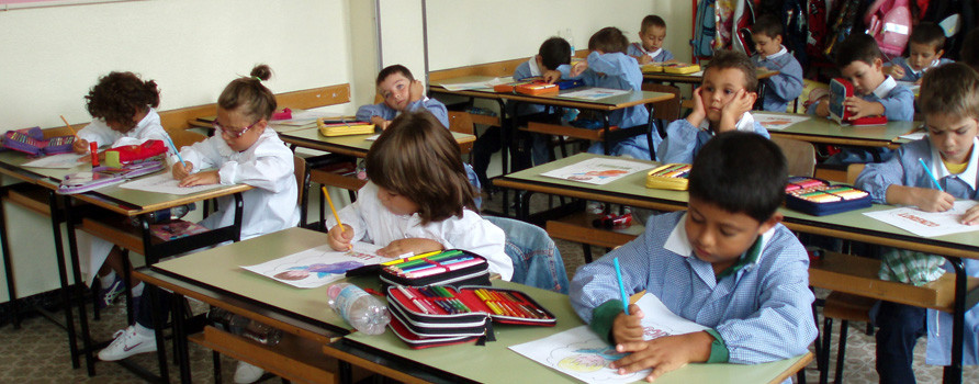Bambini impegnati a colorare sui banchi di scuola